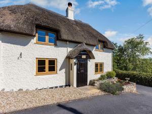 a thatch roofed cottage with a thatched roof at Honeysuckle Cottage in Axminster