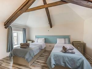 two beds in a room with wooden beams at Heath Hills in Okehampton