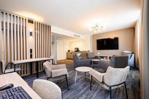 a waiting room with chairs and tables and a tv at Dorpat Hotel in Tartu