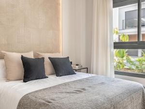1 dormitorio con cama con almohadas y ventana en Modern with swimming pool- 2Bd 2Bth- Triana en Sevilla