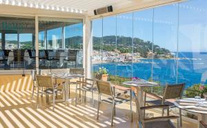 a balcony with tables and chairs and a view of the ocean at Hotel Sant Roc in Calella de Palafrugell