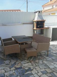 un patio con mesa, sillas y parrilla en Casa dos pelicanos 3 ROOMS en Sesimbra