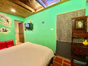 金寧鄉的住宿－彼岸古厝民宿-包棟優先--Biiann B&B，一间卧室设有一张床和绿色的墙壁