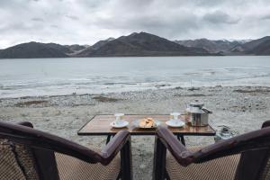 einen Tisch mit einem Teller Essen und zwei Stühlen in der Unterkunft Astrostays at Pangong Lake in Spangmik