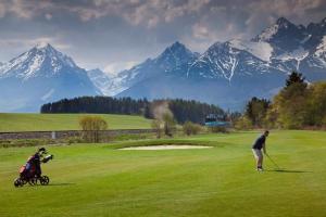 a man and a child playing golf on a golf course at Apartmán Lomnica - Vysoké Tatry in Veľká Lomnica