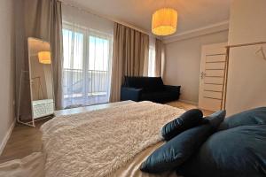 a bedroom with a bed and a couch and a window at HARMONY Apartment - Zator Energylandia in Zator