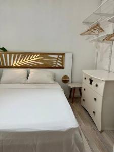a bedroom with a white bed and a dresser at Heitiare lodge in Paea