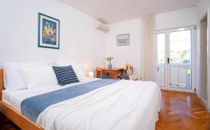 a white bedroom with a large bed and a window at Guesthouse Novak in Hvar