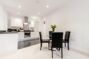 
a kitchen with a table, chairs and a refrigerator at Roomspace Serviced Apartments - Nouvelle House in Sutton
