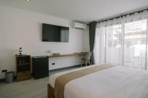 a bedroom with a bed and a tv and a window at ONE LODGE Pattaya in Pattaya Central