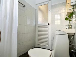 La salle de bains blanche est pourvue d'une douche et de toilettes. dans l'établissement Villa By The Beach Goa -Breakfast Included, à Benaulim