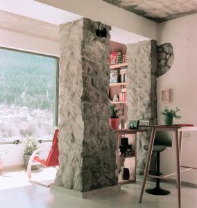 a room with a stone wall with a desk and a window at Hotel Lamish in Mestia