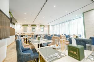 a dining room with tables and blue chairs at Azur Regency Hotel Apartments in Dubai