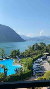 a large swimming pool with cars parked next to the water at Apartment Bella Vista Lugano in Bissone