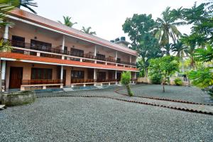 a building with a gravel driveway in front of it at Hotel Cocobeach Kovalam in Kovalam
