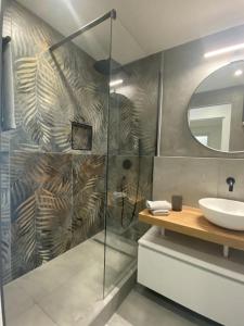 a bathroom with a shower with a sink and a mirror at Apartment Bella Vista Lugano in Bissone