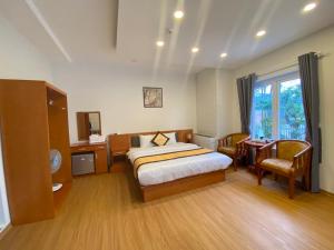 a bedroom with a bed and a desk and a window at Cherry Luxury Hotel in Da Lat