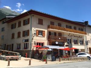 een groot gebouw met rode parasols ervoor bij Appartements avec draps inclus dans le tarif in Lanslebourg-Mont-Cenis