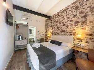 1 dormitorio con 1 cama grande y pared de piedra en Soléa House Hotel Boutique en Benicàssim