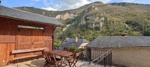 una mesa y sillas en un balcón con una montaña en Gîte de la Batelière, en La Malène