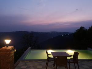 a patio with a table and chairs and a swimming pool at Eleson Cliffside Retreat in Panchgani