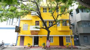 a yellow building with a tree in front of it at MOHI VILLA in Pondicherry