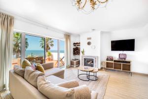 a living room with a couch and a tv at Big Wave Front Row - Two Bedroom in Nazaré