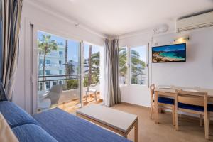 ein Wohnzimmer mit einem blauen Sofa und einem Tisch mit einem Schreibtisch in der Unterkunft Apartamentos Bossa Bay - MC Apartamentos Ibiza in Ibiza-Stadt