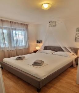um quarto com uma cama grande e lençóis brancos em Villa Casa Mia em Privlaka