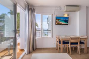 a dining room with a table and a large window at Apartamentos Bossa Bay - MC Apartamentos Ibiza in Ibiza Town