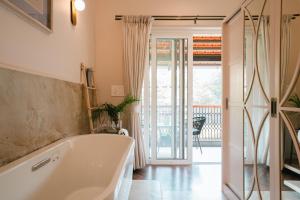 ein Bad mit einer Badewanne und einem Balkon in der Unterkunft Elivaas Opalys Luxe 4BHK Villa with Pvt Pool near Baga in Calangute