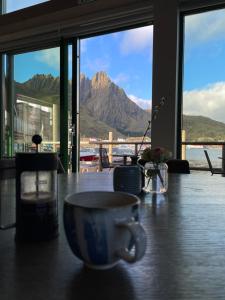 a coffee cup on a table with a view of a mountain at Hemmingodden Lodge in Ballstad