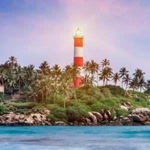 a red and white lighthouse on an island with palm trees at Hotel Cocobeach Kovalam in Kovalam +47 photos