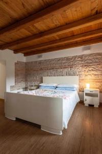 Cama grande en habitación con pared de ladrillo en B&b La Casa di Elsa, en Polcenigo