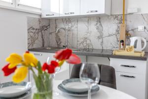 a kitchen with a table with a vase of flowers at Apartman Amal in Vukovar