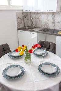 a table with plates and flowers in a kitchen at Apartman Amal in Vukovar