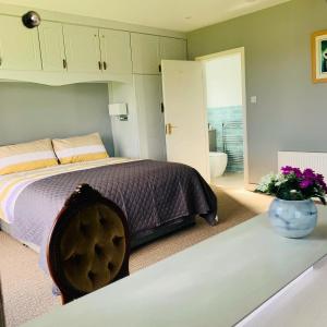 um quarto com uma cama e um vaso de flores sobre uma mesa em The Lake House Dungloe em Dungloe