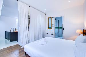 een witte slaapkamer met een groot wit bed en een badkamer bij Charming 1BR Apartment in a gated complex and a short walk from Queens Park Tube in Londen
