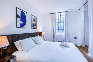 een slaapkamer met een groot wit bed en een raam bij Charming 1BR Apartment in a gated complex and a short walk from Queens Park Tube in Londen