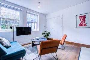 een woonkamer met een bank en een tafel bij Charming 1BR Apartment in a gated complex and a short walk from Queens Park Tube in Londen