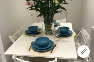 una mesa blanca con placas azules y un jarrón con flores en 1 bed apartment in West London, en Heston