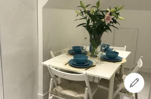 a white table with blue dishes and a vase of flowers at 1 bed apartment in West London in Heston