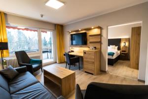 a hotel room with a couch and a desk and a bed at VitalHotel Ascona in Bad Bevensen