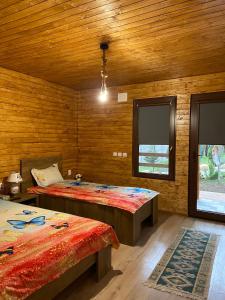 a room with two beds in a room with wooden walls at Grădina de Vară “La Cristian” in Filipeştii de Tîrg