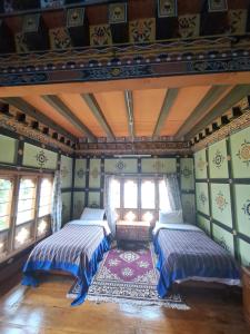 2 Betten in einem Zimmer mit grünen Wänden und Fenstern in der Unterkunft Mendrelgang Homestay in Punākha