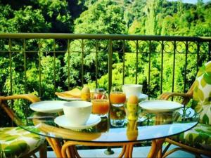een glazen tafel met kopjes en drankjes op een balkon bij Riverside Suite in Kalopanayiotis