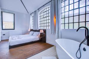 een slaapkamer met een bed, een bad en ramen bij Stunning Penthouse Apartment Close to Queen's Park - Mega Fast Internet in Londen
