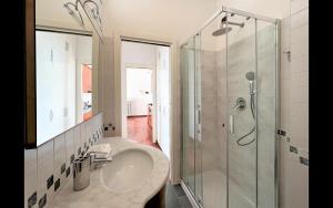 ein Bad mit einem Waschbecken und einer Glasdusche in der Unterkunft Larius Apartment Carate Urio in Laglio