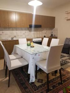 a dining room table with white chairs and a kitchen at The Quiet Corner in Kalamata
