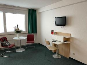um quarto com uma mesa e uma televisão na parede em A&S Ferienzentrum Oberhof em Oberhof
